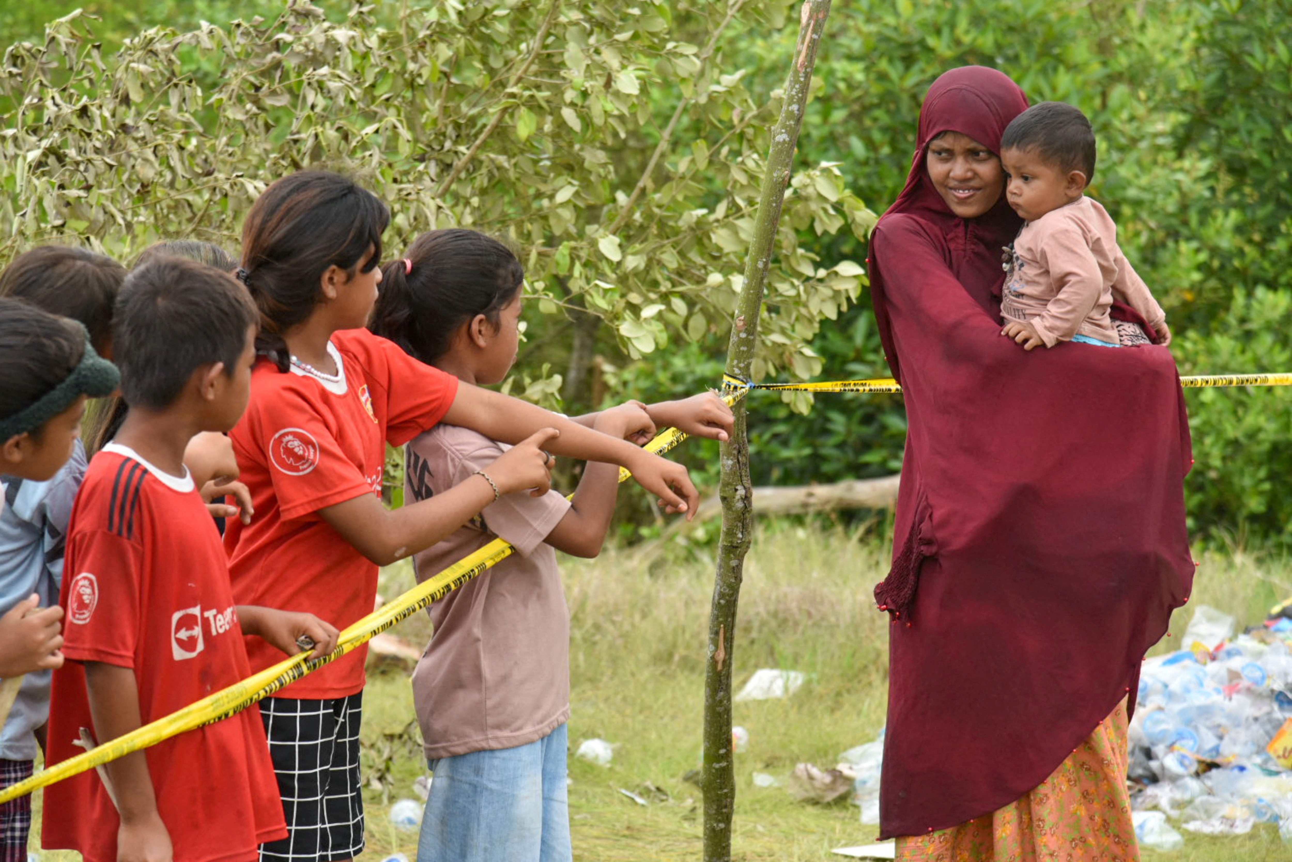 A Rohingya Muslim woman carries her child as she greets locals at a temporary shelter, following their arrival in Karang Gading village
