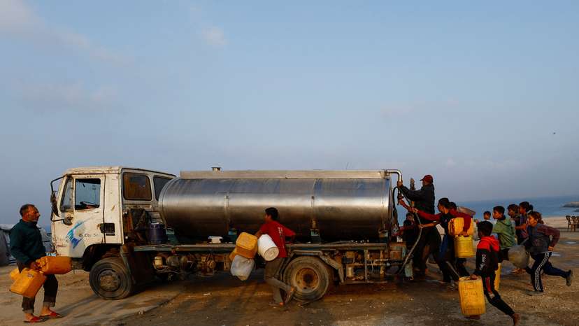 Displaced Palestinians run to fill containers with water amid a ceasefire between Israel and Hamas, in Gaza City