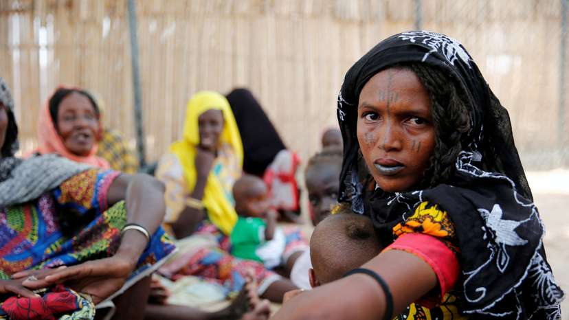 FILE PHOTO: Woman sits outside a shed as she waits for food rations at IDP camp on the outskirts of Maiduguri