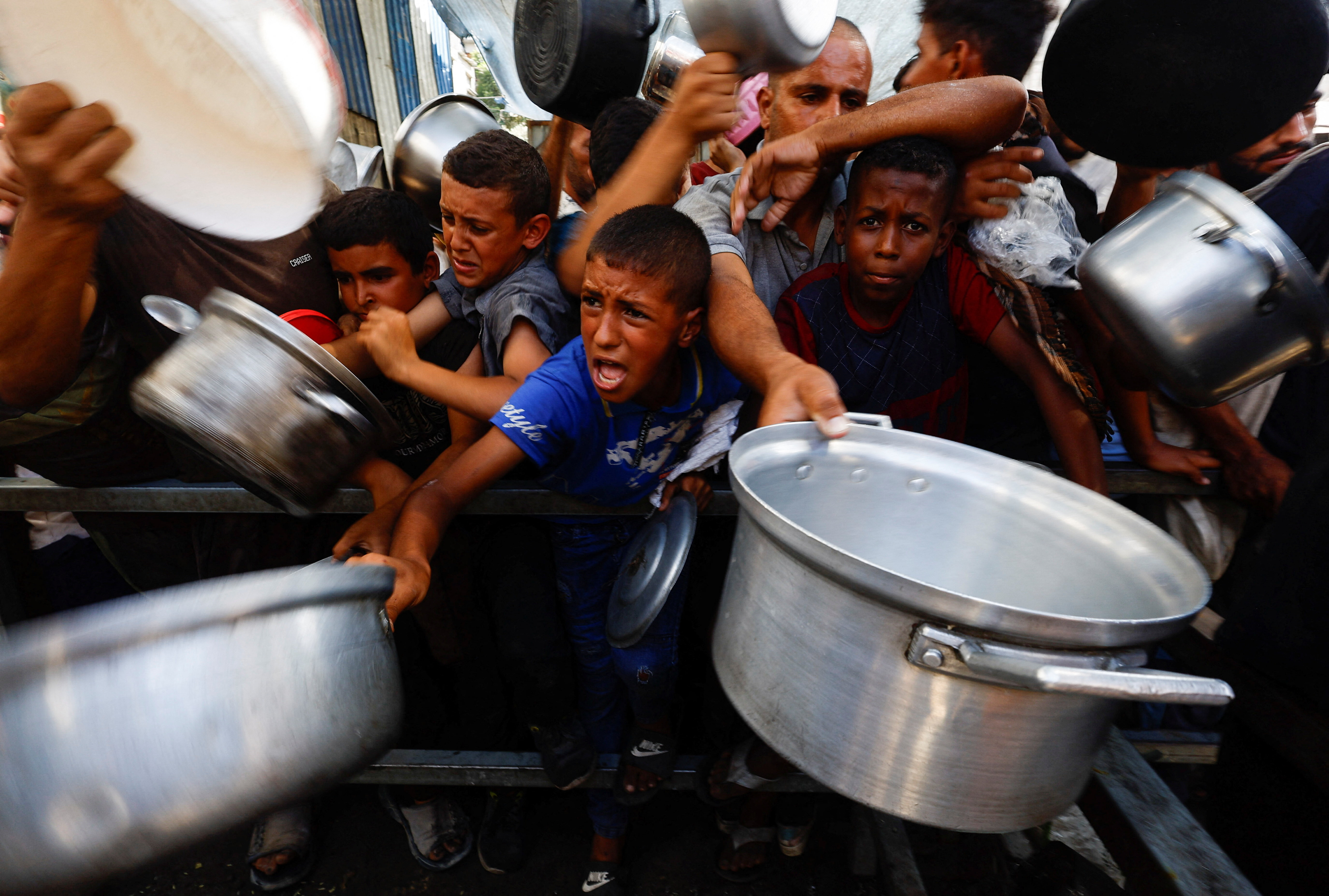 Palestinians gather to receive food from a charity kitchen, in Nuseirat