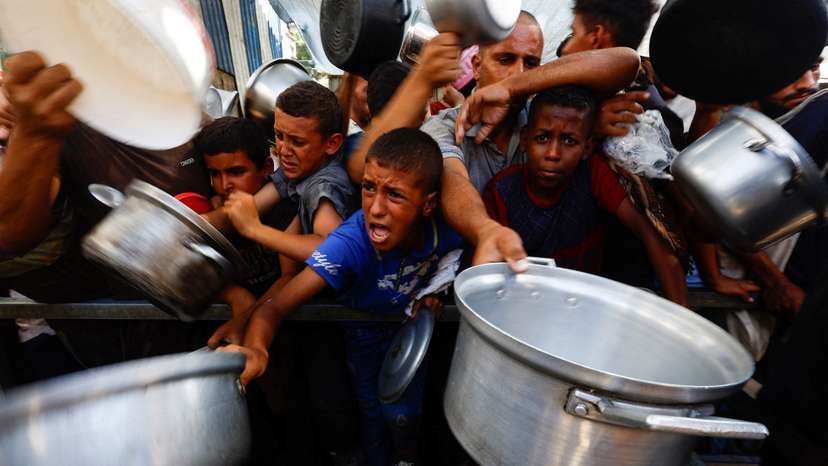 Palestinians gather to receive food from a charity kitchen, in Nuseirat