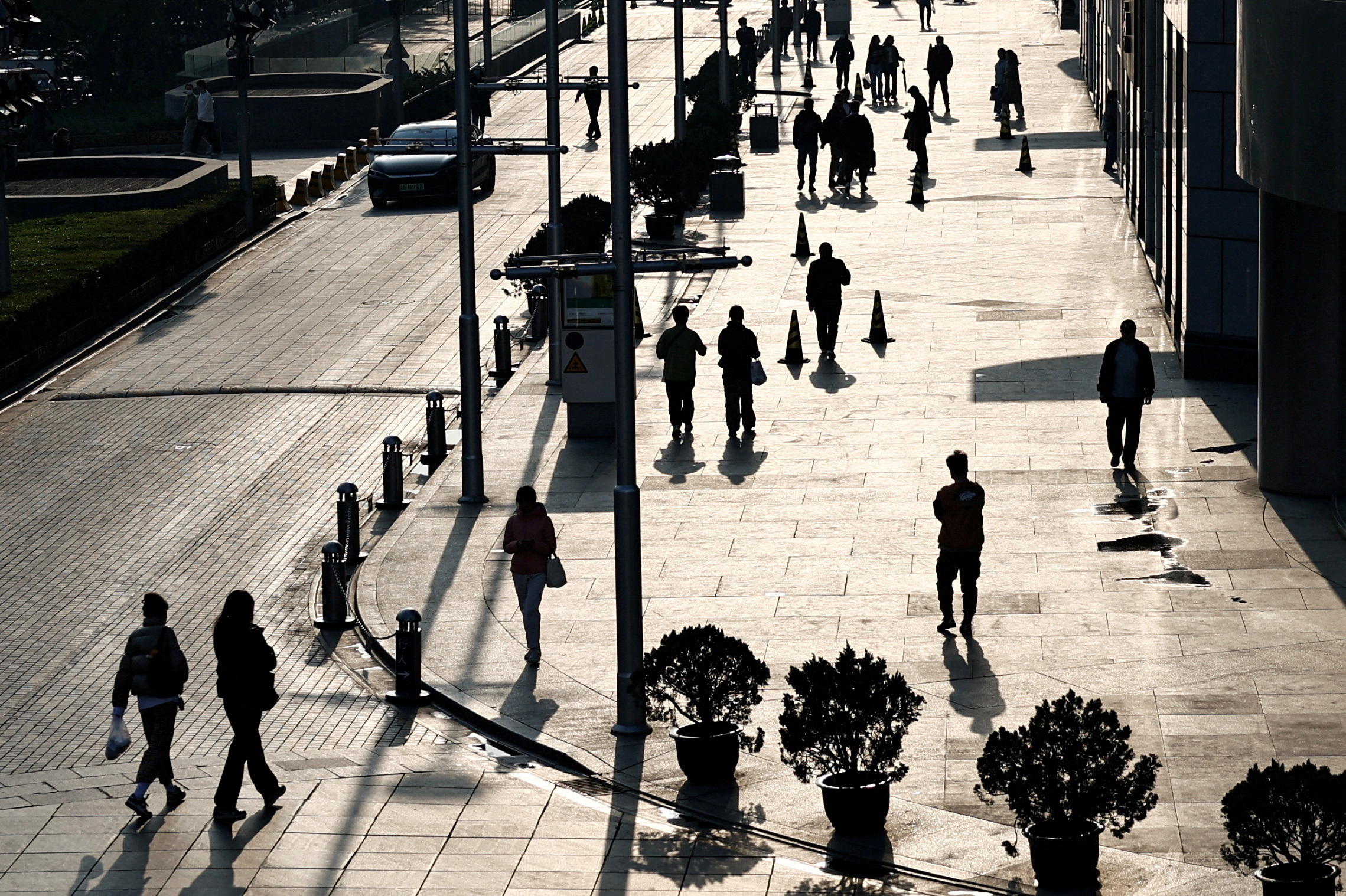FILE PHOTO: People walk past an office and shopping complex in Beijing