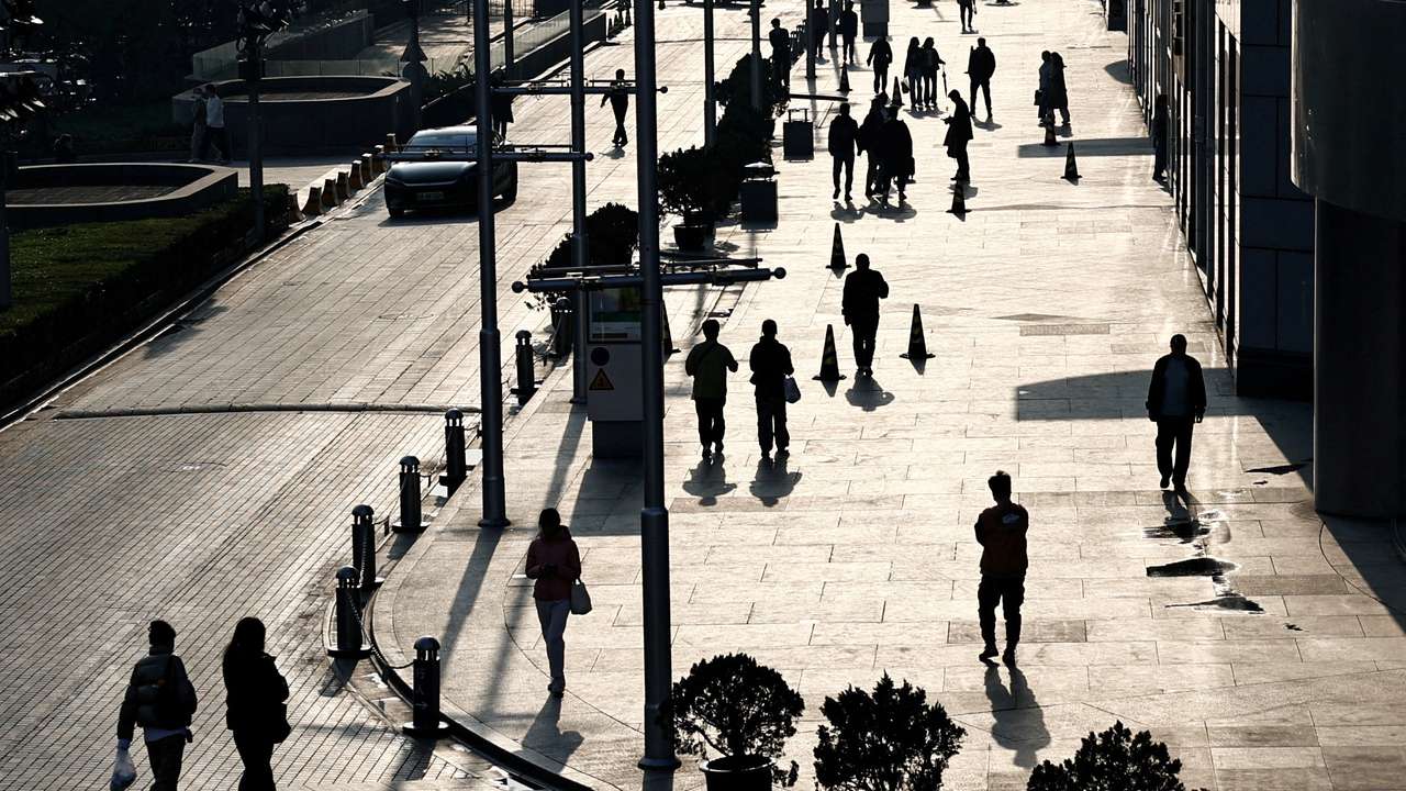 FILE PHOTO: People walk past an office and shopping complex in Beijing