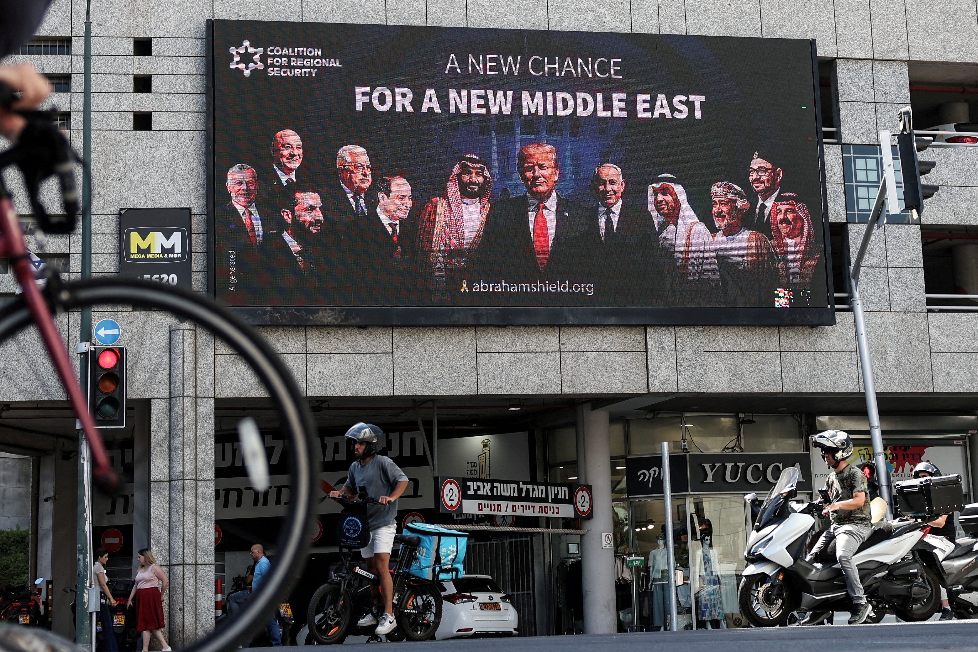 People walk by a billboard sponsored by the Coalition for Regional Security calling for the expansion of the Abraham Accords, in Ramat Gan