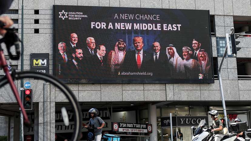 People walk by a billboard sponsored by the Coalition for Regional Security calling for the expansion of the Abraham Accords, in Ramat Gan