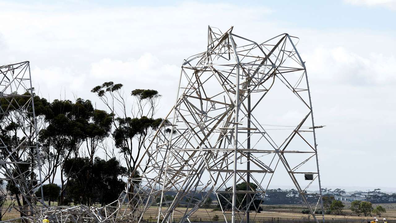 Workers inspect damaged transmission towers at Anakie