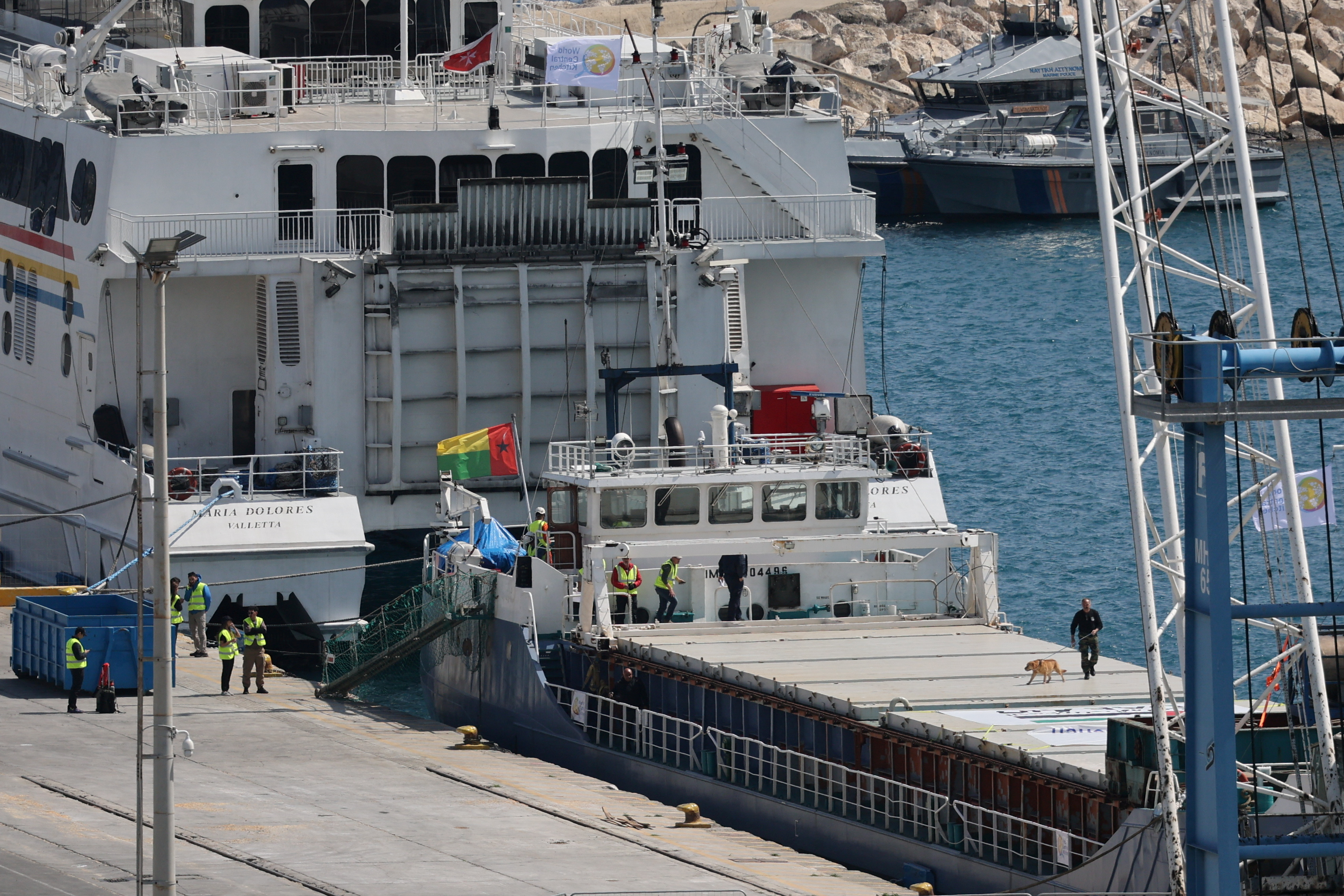 A police officer uses a sniffer dog to inspect the cargo ship loaded with humanitarian aid for Gaza in the port of Larnaca