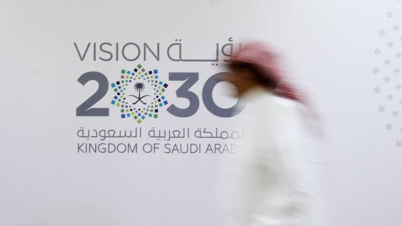 A Saudi man walks past the logo of Vision 2030 after a news conference, in Jeddah