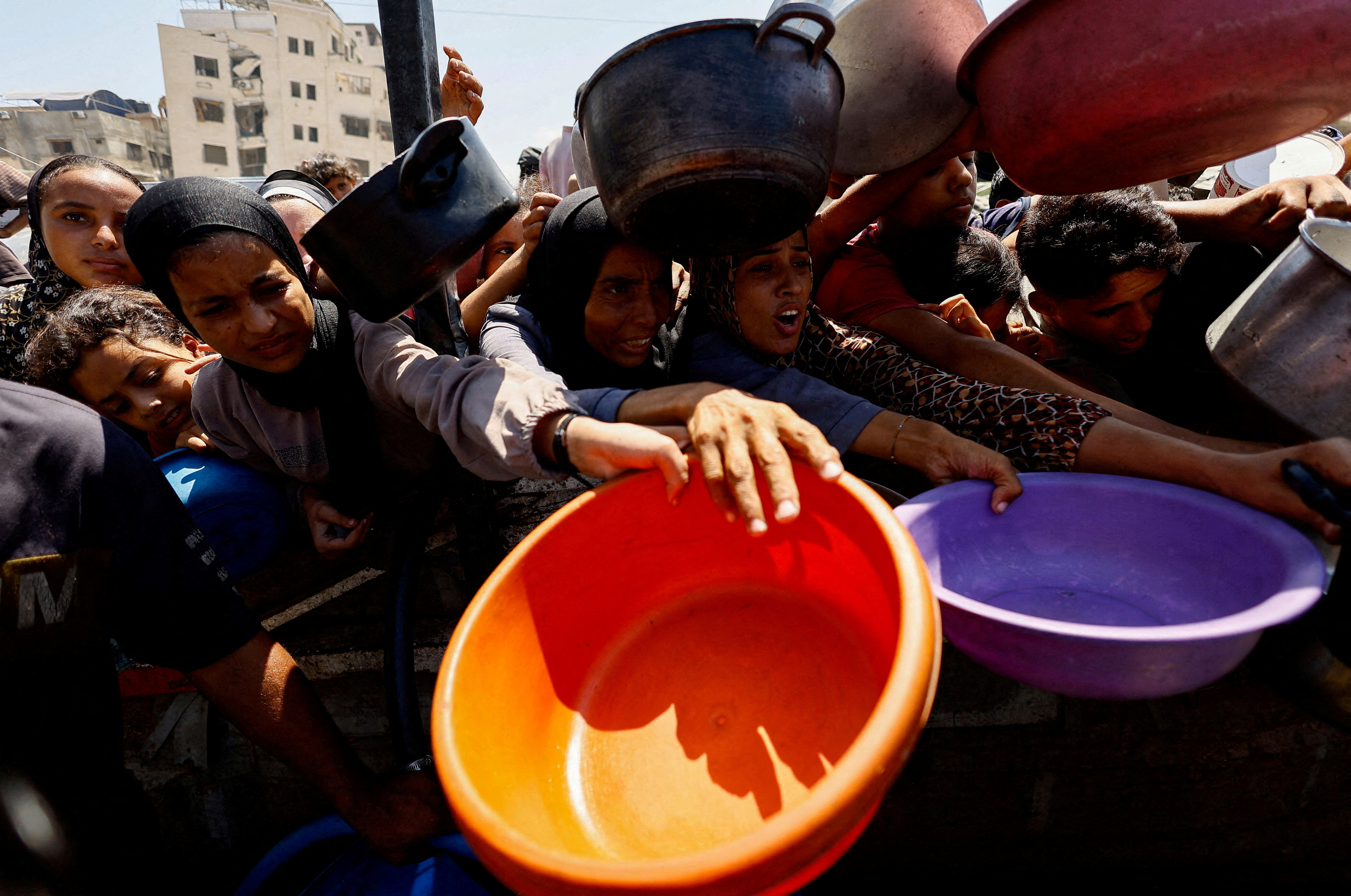 FILE PHOTO: Palestinians wait to receive food from a charity kitchen, in Gaza City