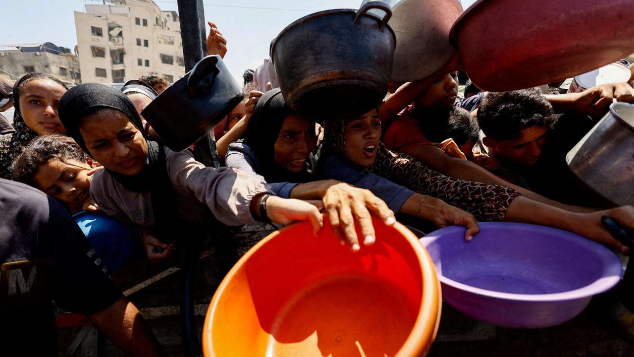 FILE PHOTO: Palestinians wait to receive food from a charity kitchen, in Gaza City