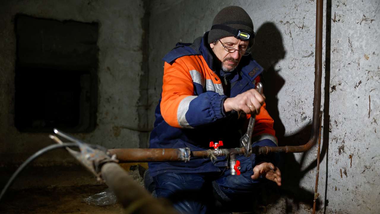 Ukrainian Railways employee Volodymyr Vasiliev works inside a basement of an apartment building to restore heating and wated supply for residents in Kyiv