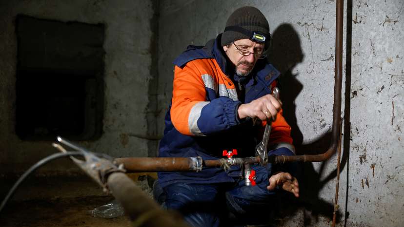 Ukrainian Railways employee Volodymyr Vasiliev works inside a basement of an apartment building to restore heating and wated supply for residents in Kyiv