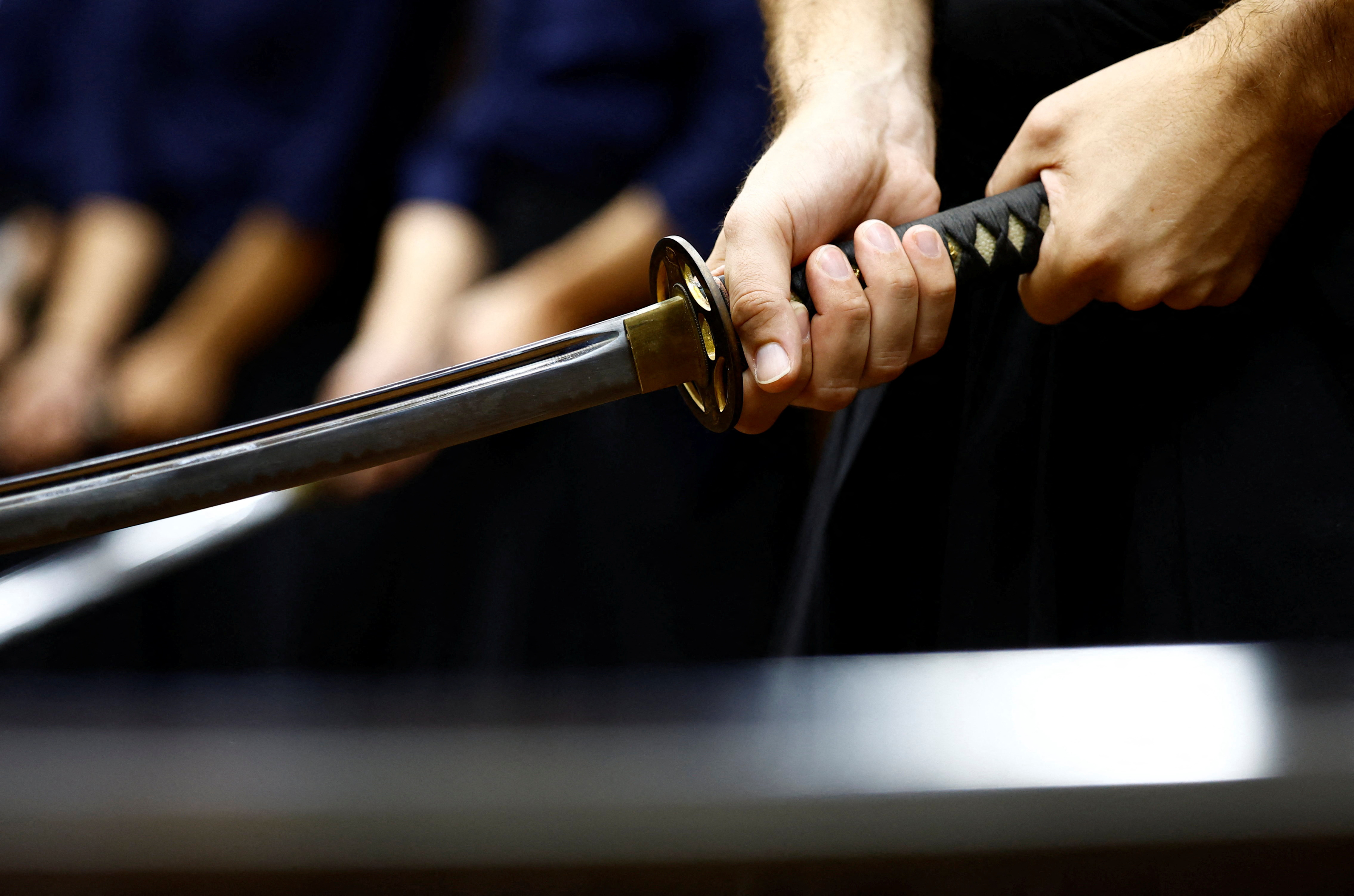 Tourists from abroad hold an imitation Japanese sword as they take part in a Japanese sword-cutting experience at Samurai Theater Tokyo in Tokyo