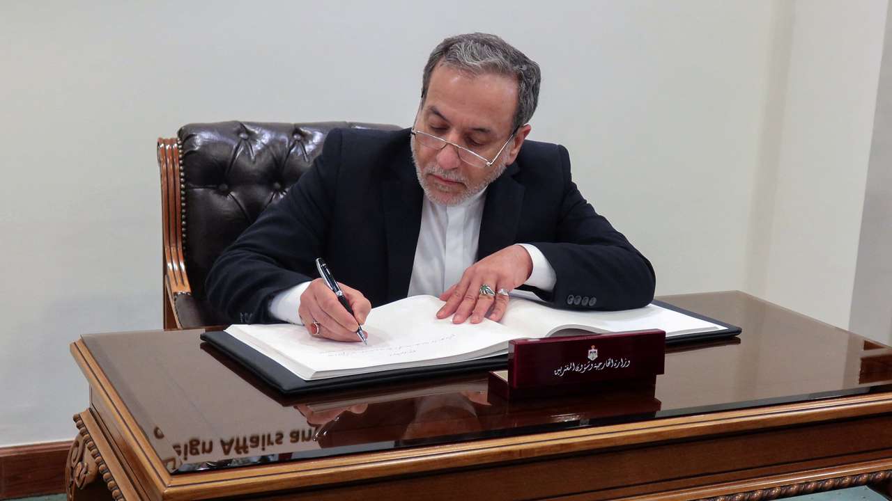 Iran's Foreign Minister Abbas Araqchi signs a guest book at the Jordanian Foreign Ministry in Amman