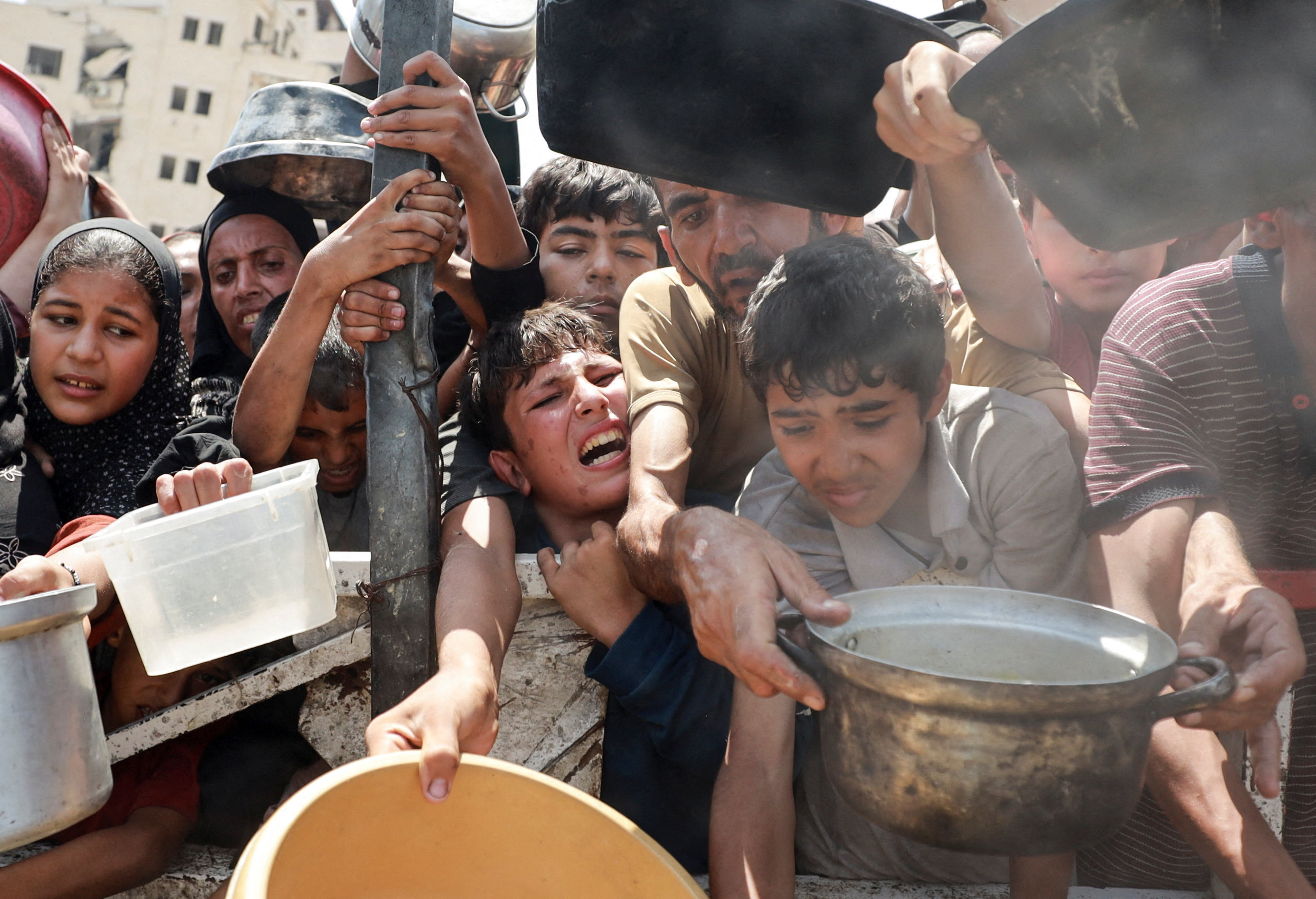 Palestinians wait to receive food from a charity kitchen, in Gaza City