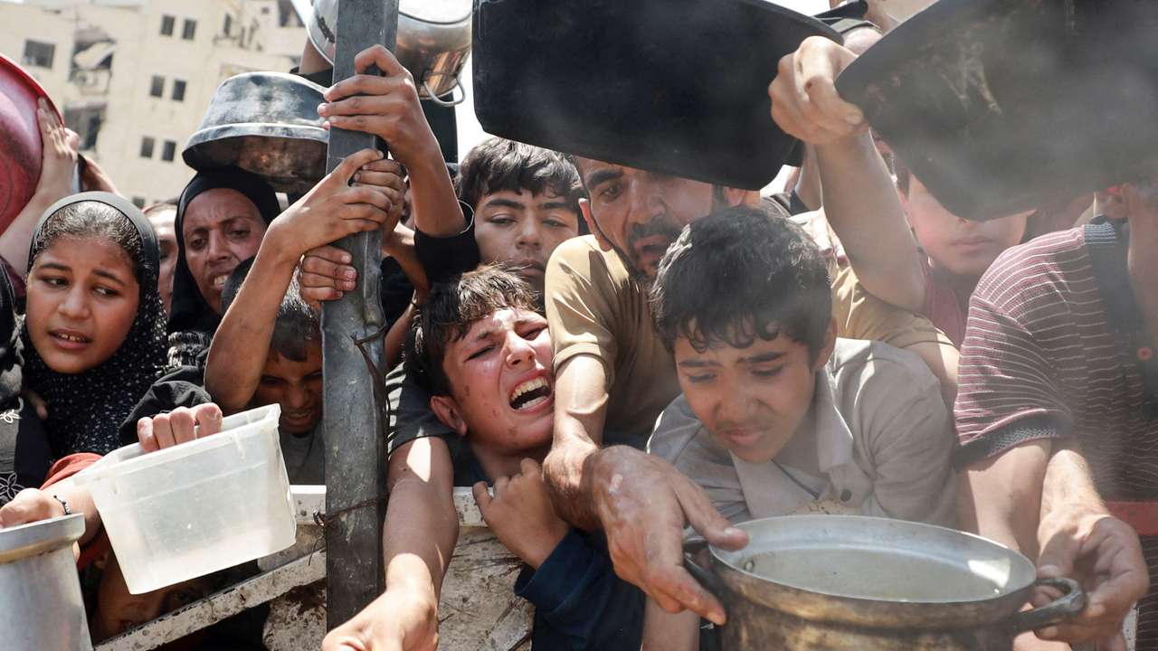 Palestinians wait to receive food from a charity kitchen, in Gaza City