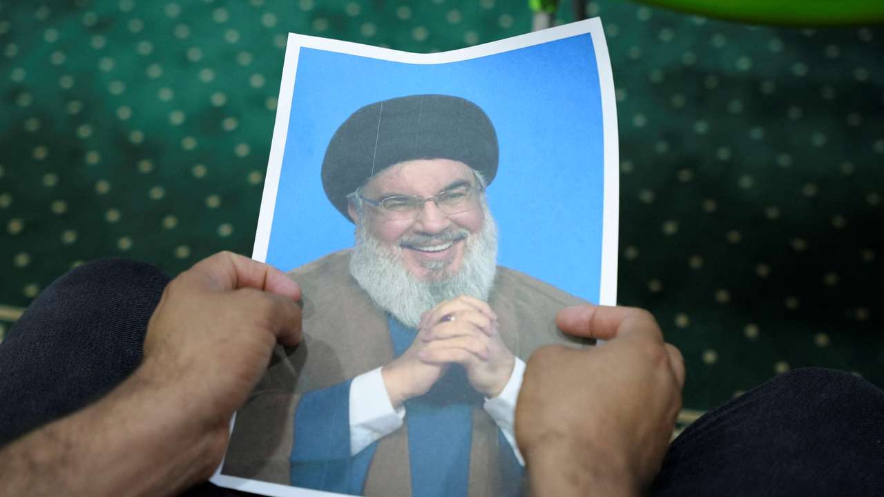 An Iraqi volunteer holds a picture of Lebanon's Hezbollah leader Nasrallah while registering his name to support Hezbollah, in Basra