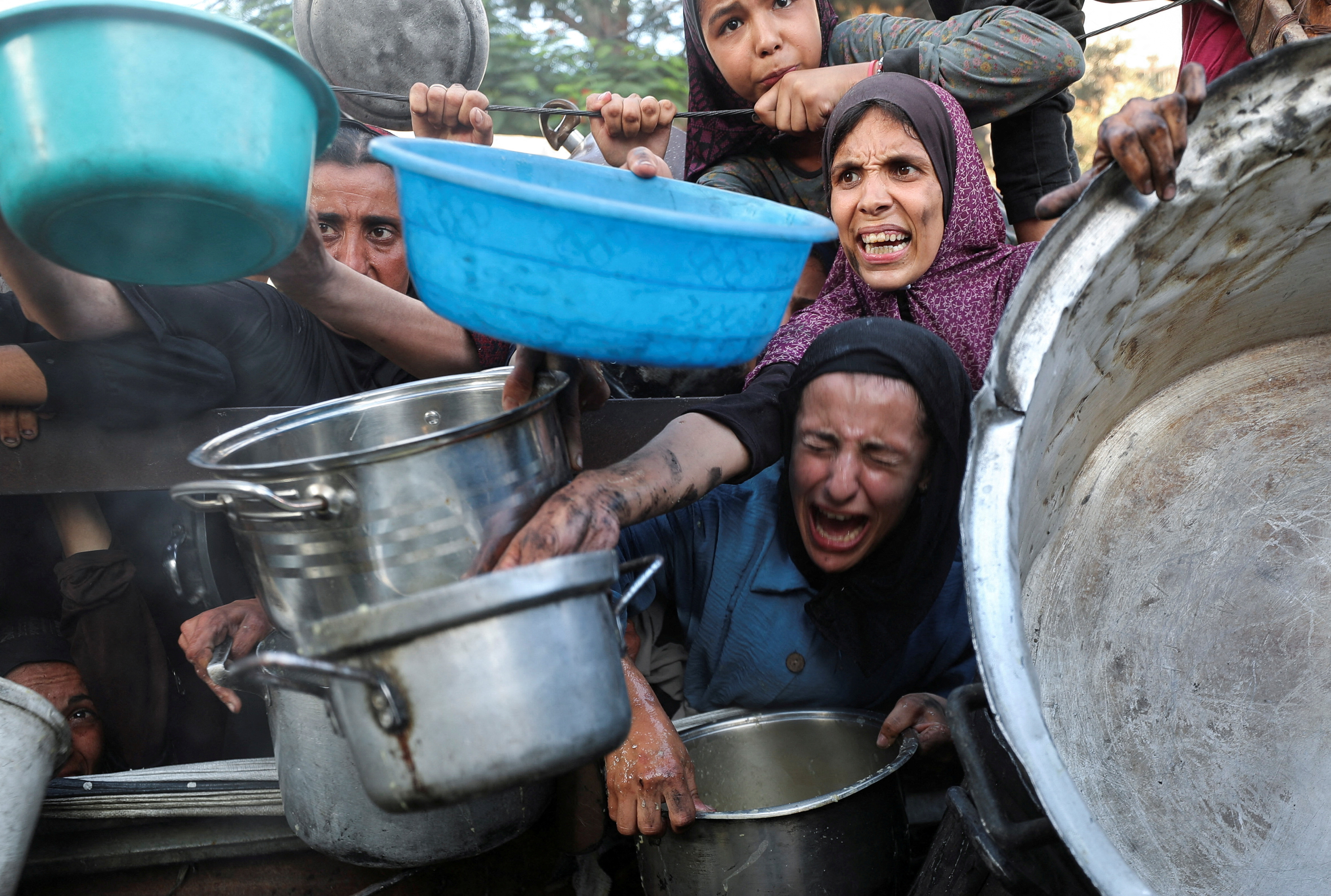Palestinians wait to receive food from a charity kitchen, amid a hunger crisis, in Gaza City