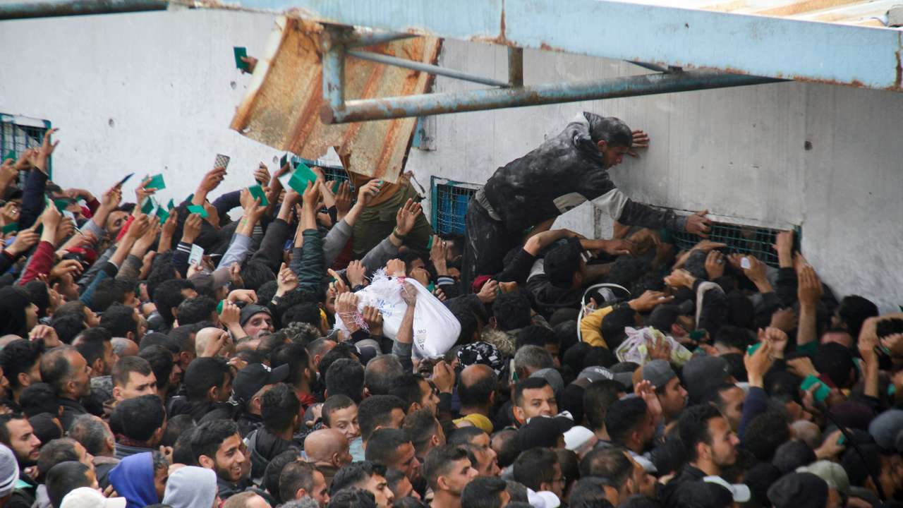 Palestinians gather to receive aid outside an UNRWA warehouse in Gaza City