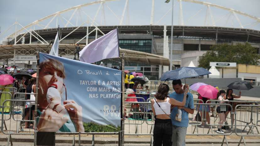 A couple protect themselves with an umbrella for high temperatures, wait before the Taylor Swift concert in Rio de Janeiro