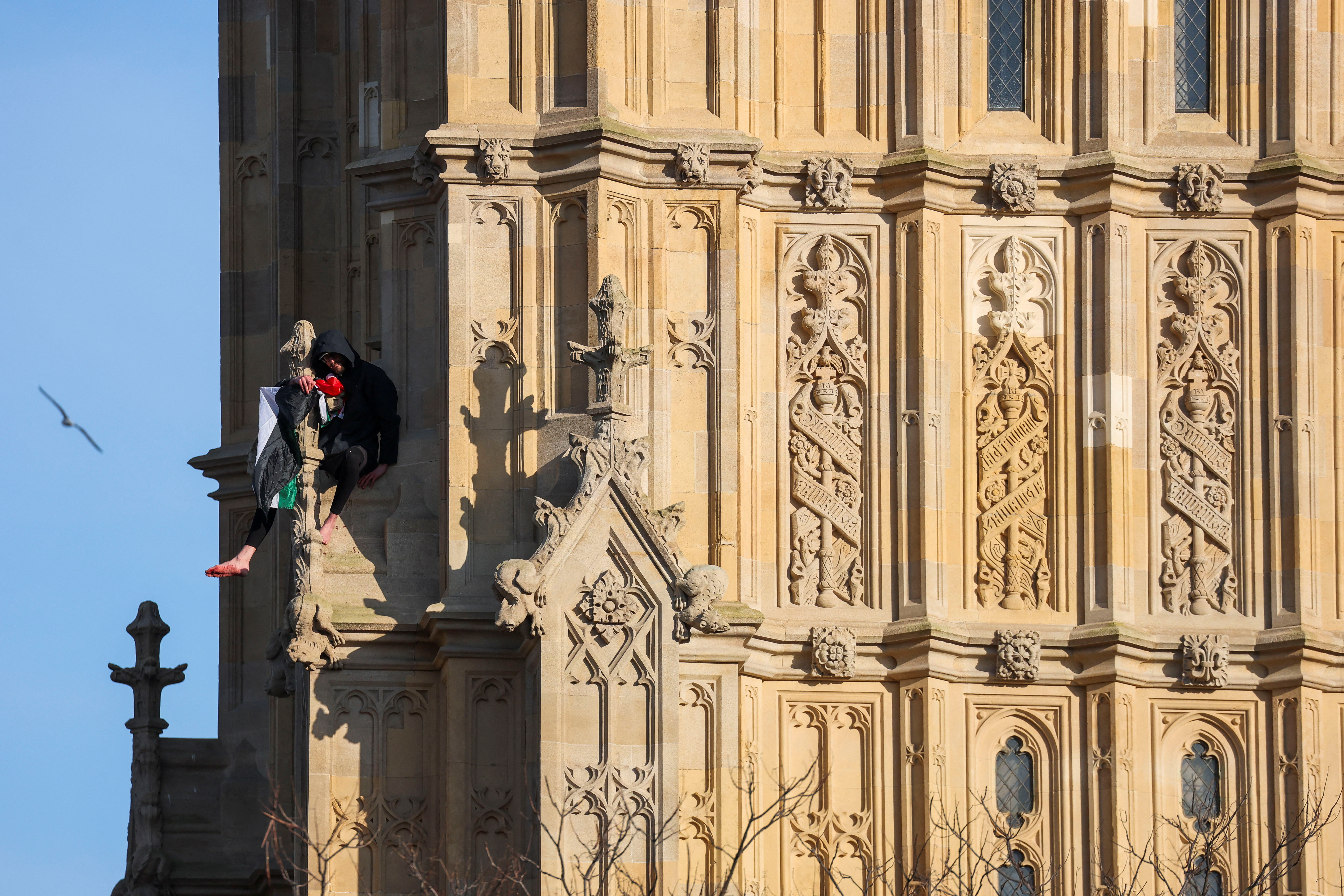 A man holding a Palestinian flag climbs Big Ben in London