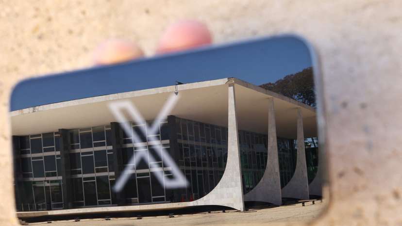The logo of social media platform X is seen on a mobile phone next to a reflection of Brazil's Supreme Court in this illustration taken August 30, 2024, in Brasilia