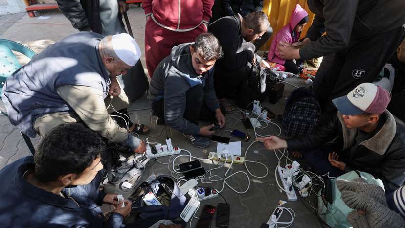 Palestinians charge their devices outside the Emirati hospital in Rafah