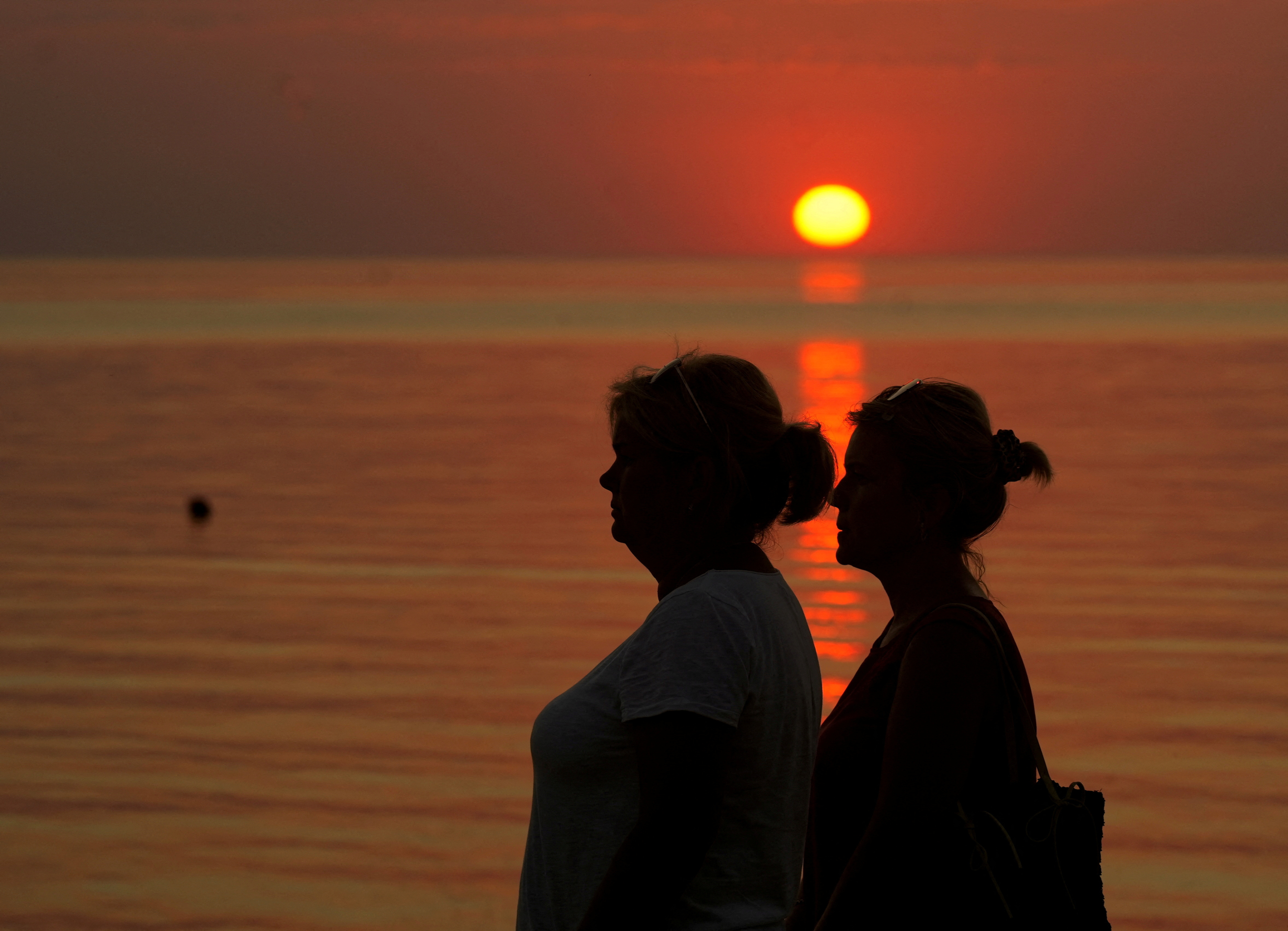 FILE PHOTO: People watch sunset on the seaside in Saulkrasti, Latvia