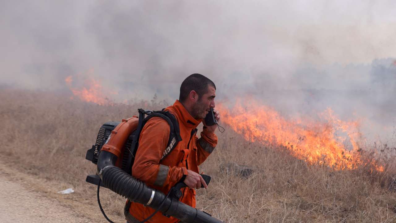 A man attempts to extinguish flames following a rocket attack from Lebanon, in the Israeli-occupied Golan Heights