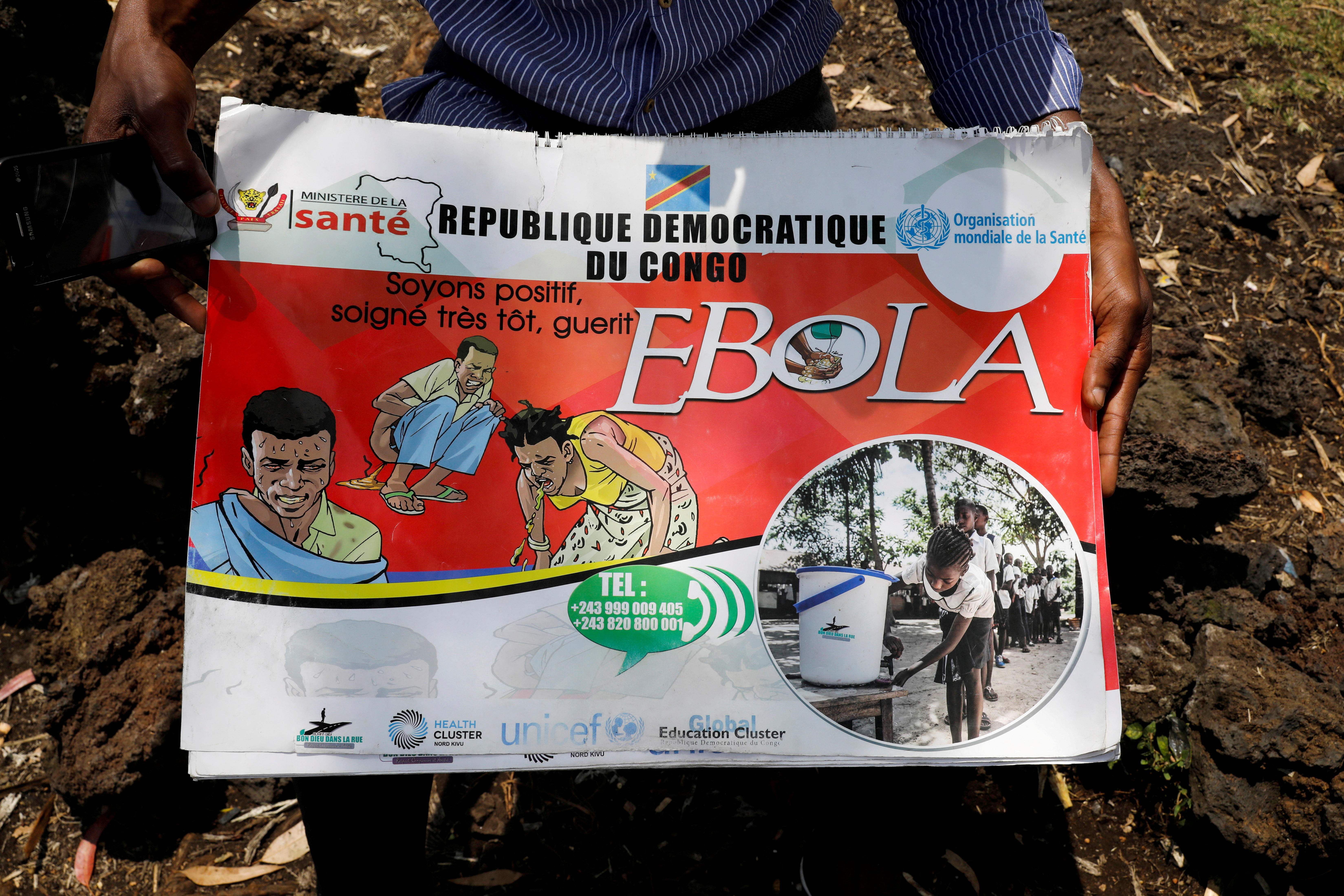 FILE PHOTO: Congolese volunteer Ferdinand Tangenyi displays a flip book he uses to inform people about the Ebola virus, in Goma