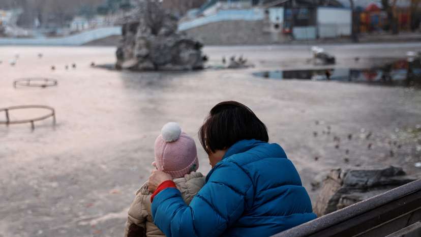 A woman and a child sit in a park in Beijing
