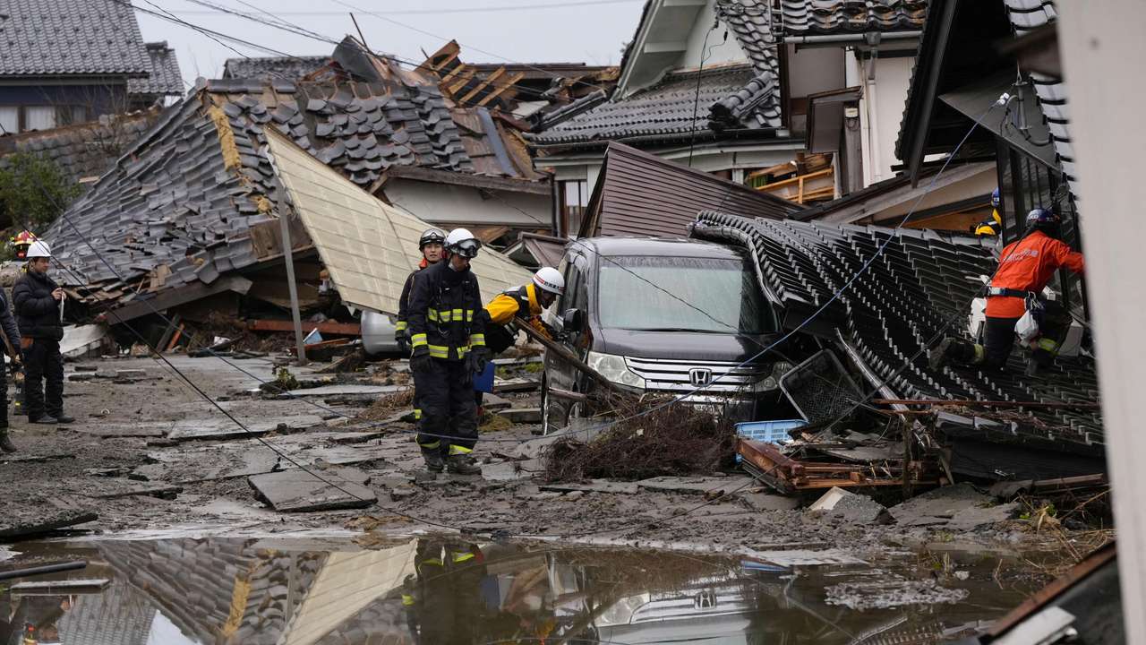 Firefighters and police officers conduct search and rescue operations at a tsunami-devastated residential area in Suzu