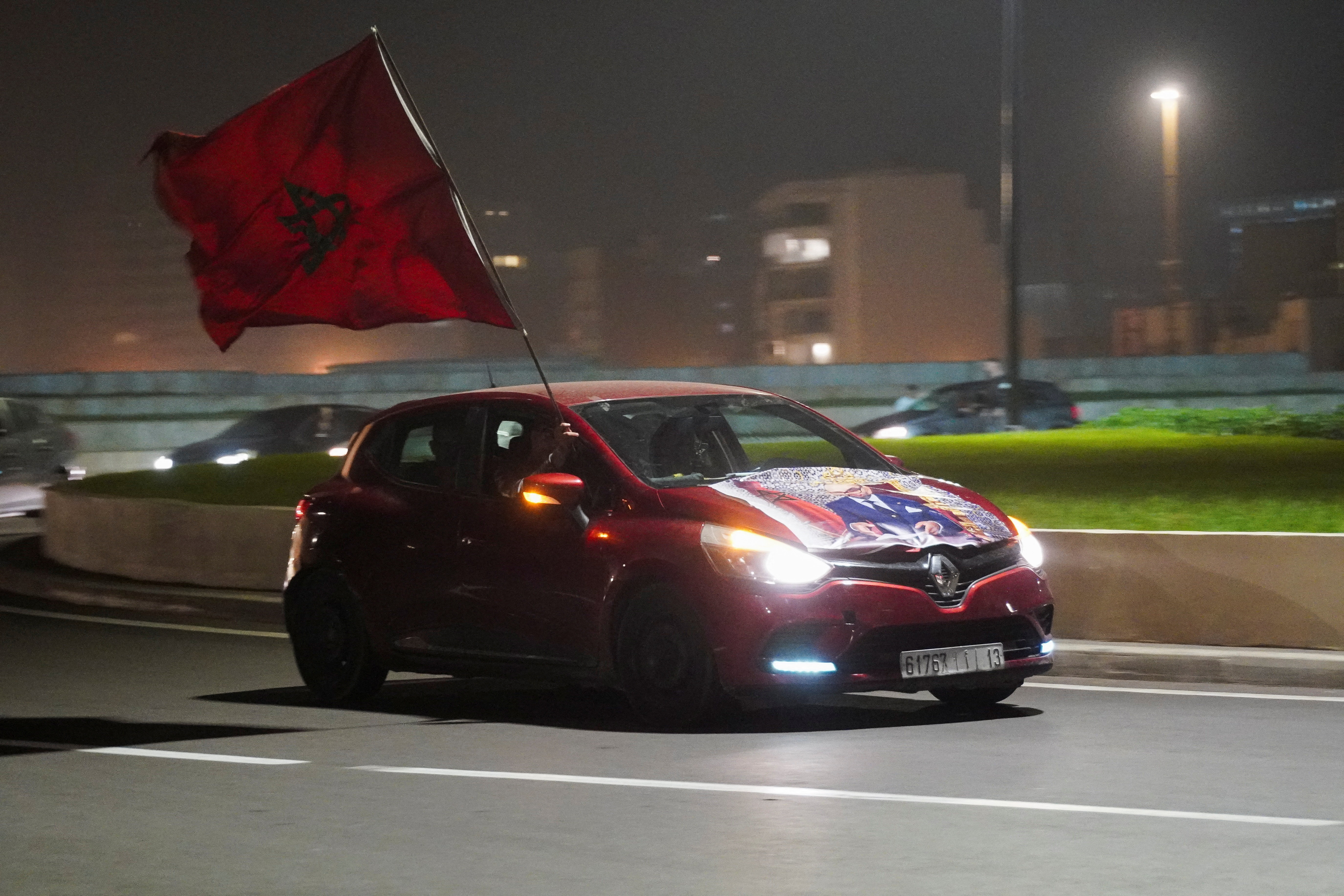 A Moroccan man holds the national flag while sitting inside a car in Casablanca