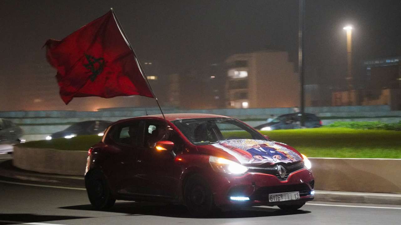 A Moroccan man holds the national flag while sitting inside a car in Casablanca