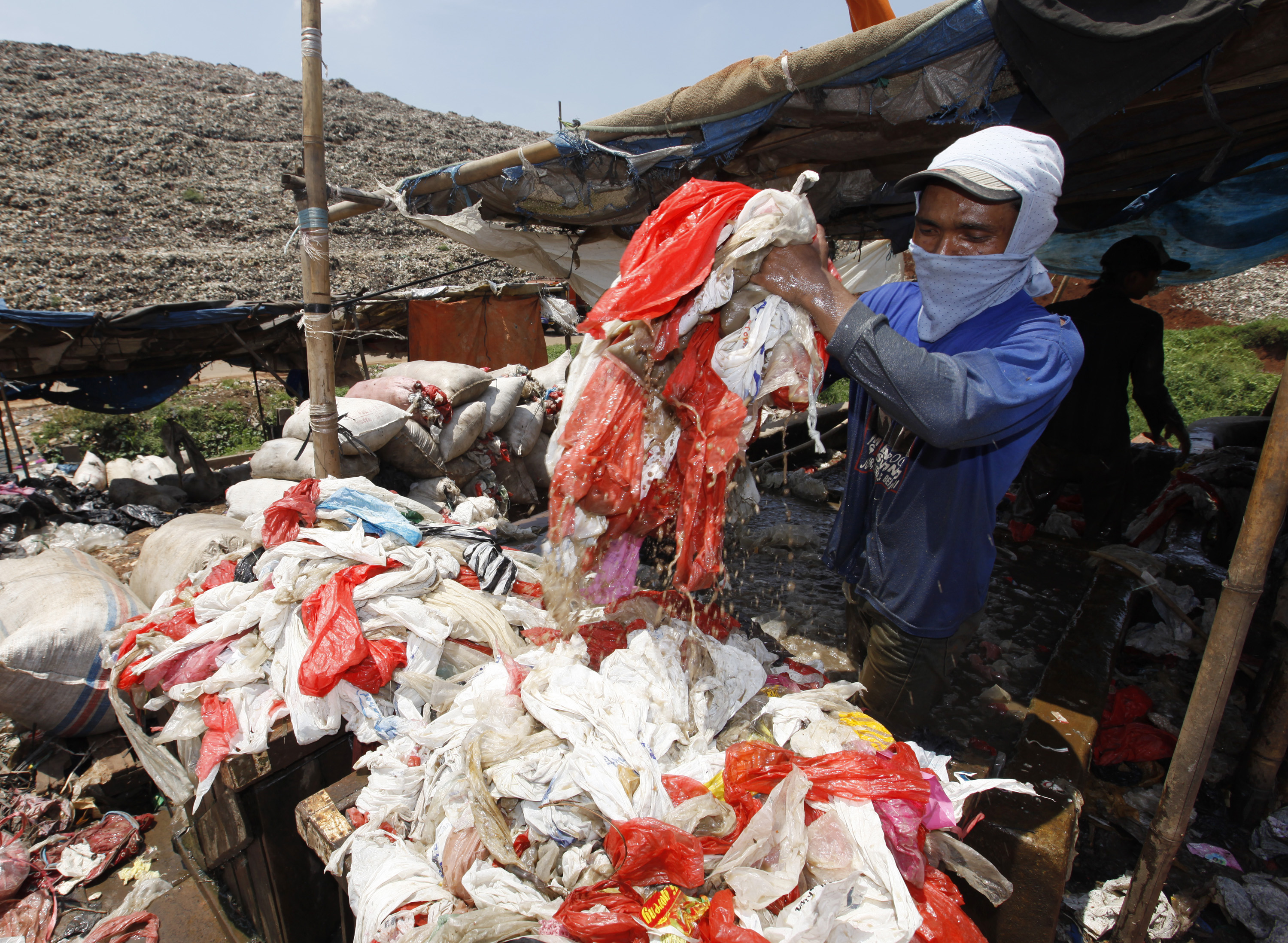 Scavenger washes plastics for recycling at Jakarta's main garbage dump at Bantar Gebang district