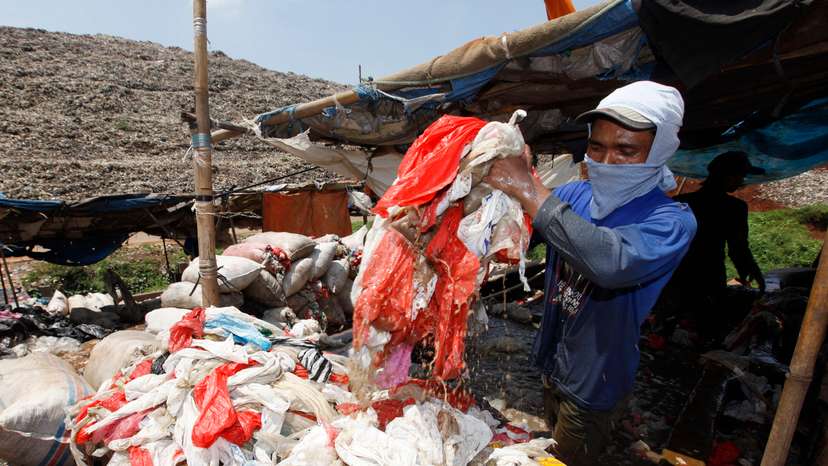 Scavenger washes plastics for recycling at Jakarta's main garbage dump at Bantar Gebang district