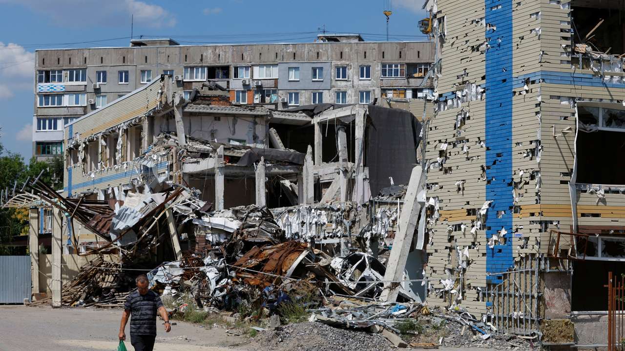 FILE PHOTO: A man walks past a destroyed building in Mariupol
