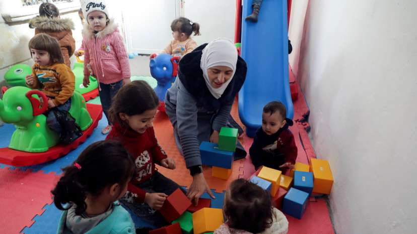 Safaa Kamel, a teacher, plays with children at a school in the northern Syrian town of Afrin