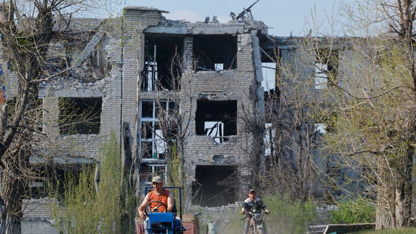 Men ride vehicles near a destroyed building in Toshkivka amid Russia-Ukraine conflict