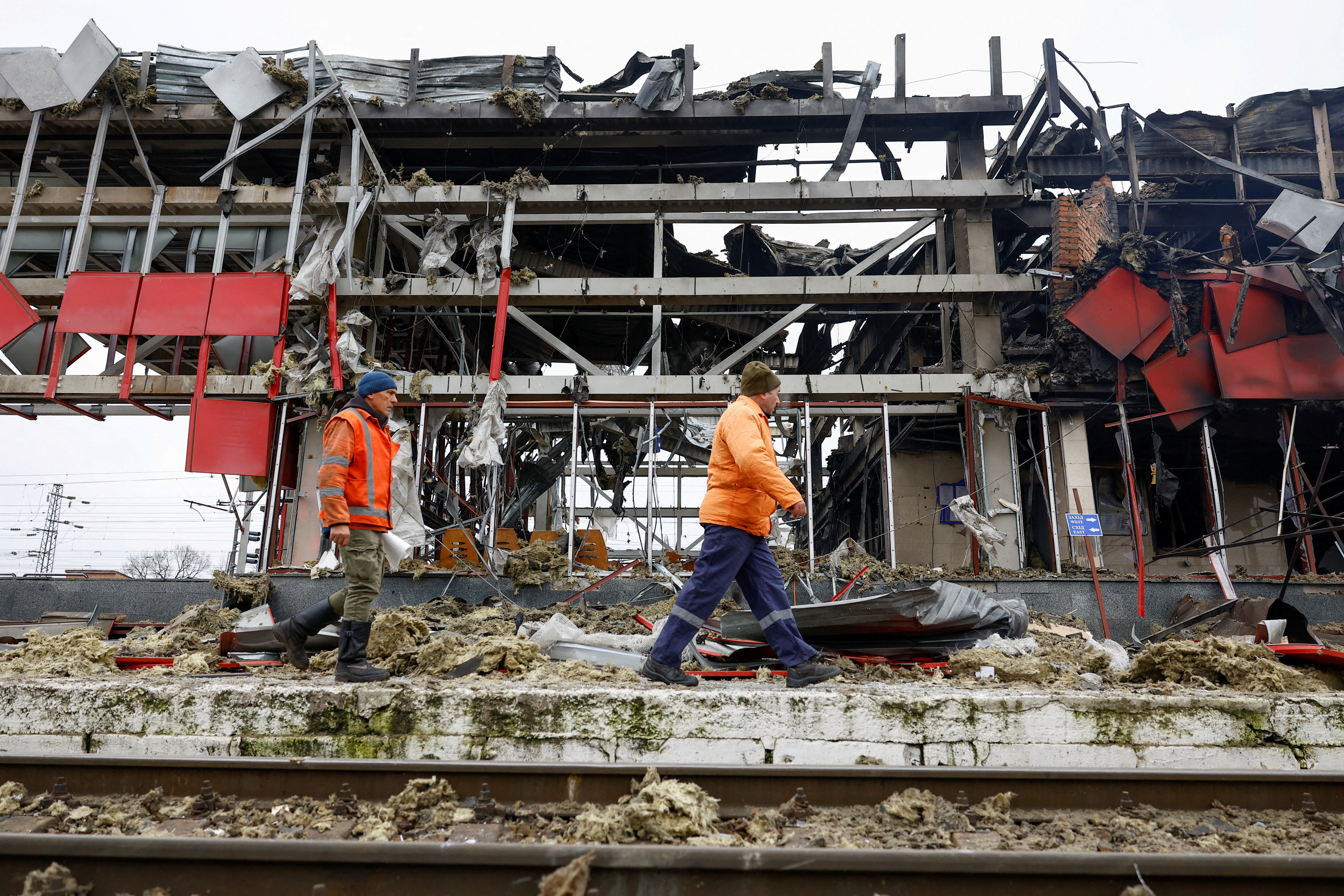 FILE PHOTO: Railway employees walk next to a railway station building hit during Russian missile and drone strikes in the town of Fastiv, Ukraine
