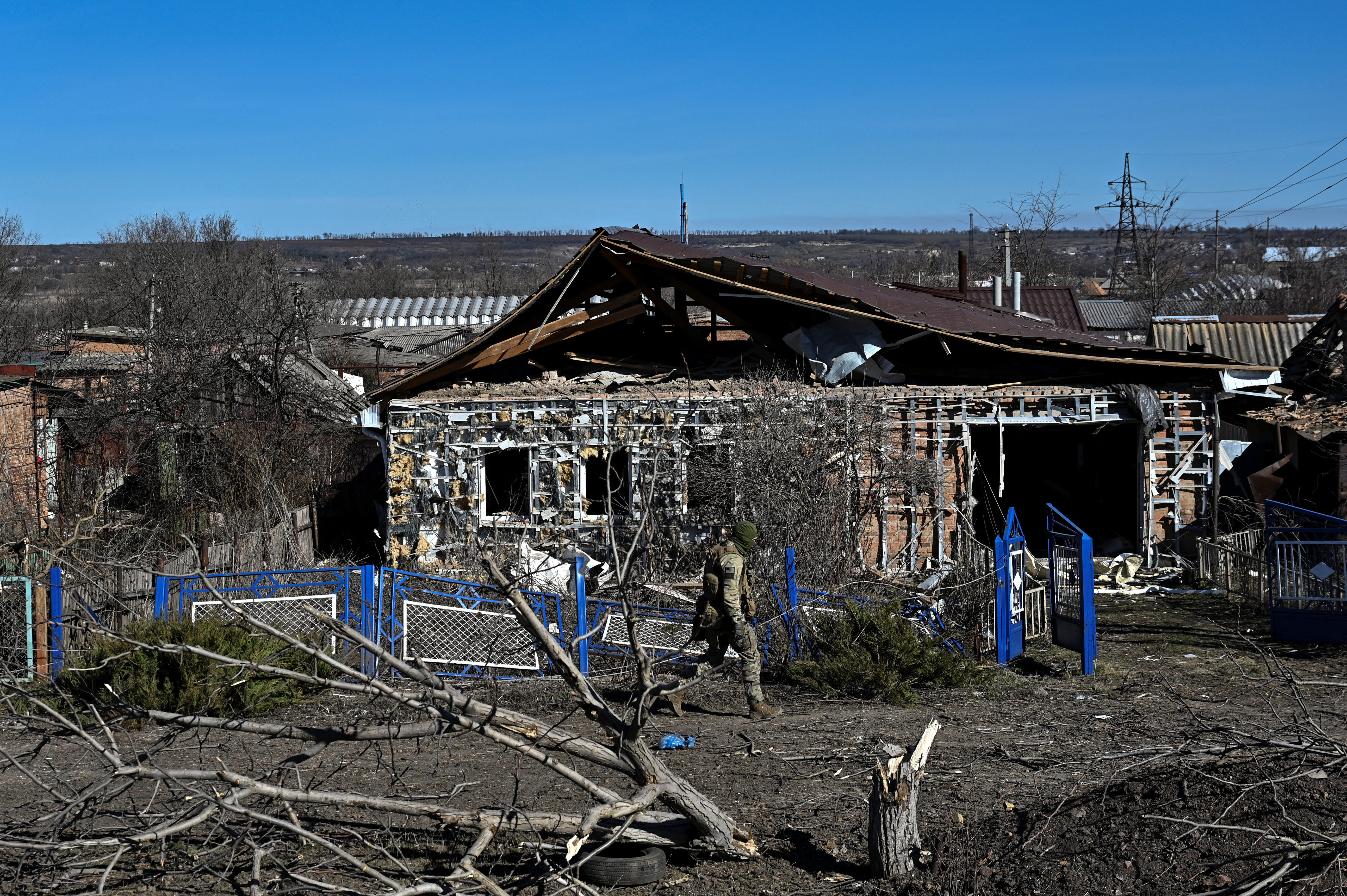 Police officer walks past a damaged house in the frontline town of Orikhiv