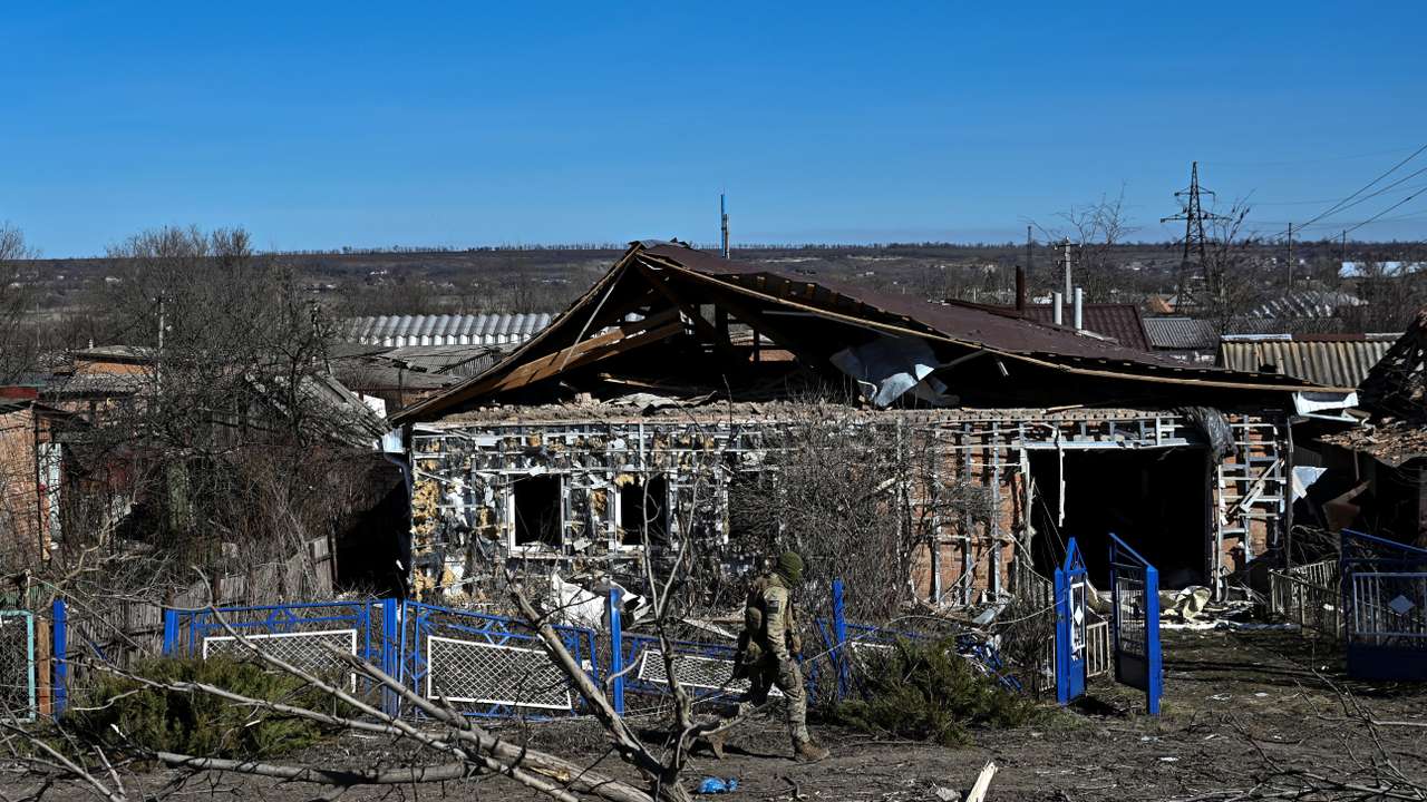 Police officer walks past a damaged house in the frontline town of Orikhiv