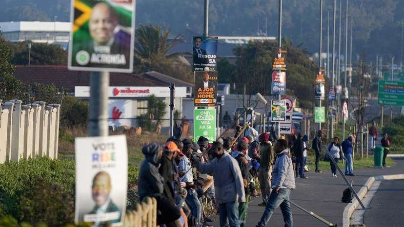 FILE PHOTO: Job seekers sit beneath campaign posters for the South African general elections, in Cape Town
