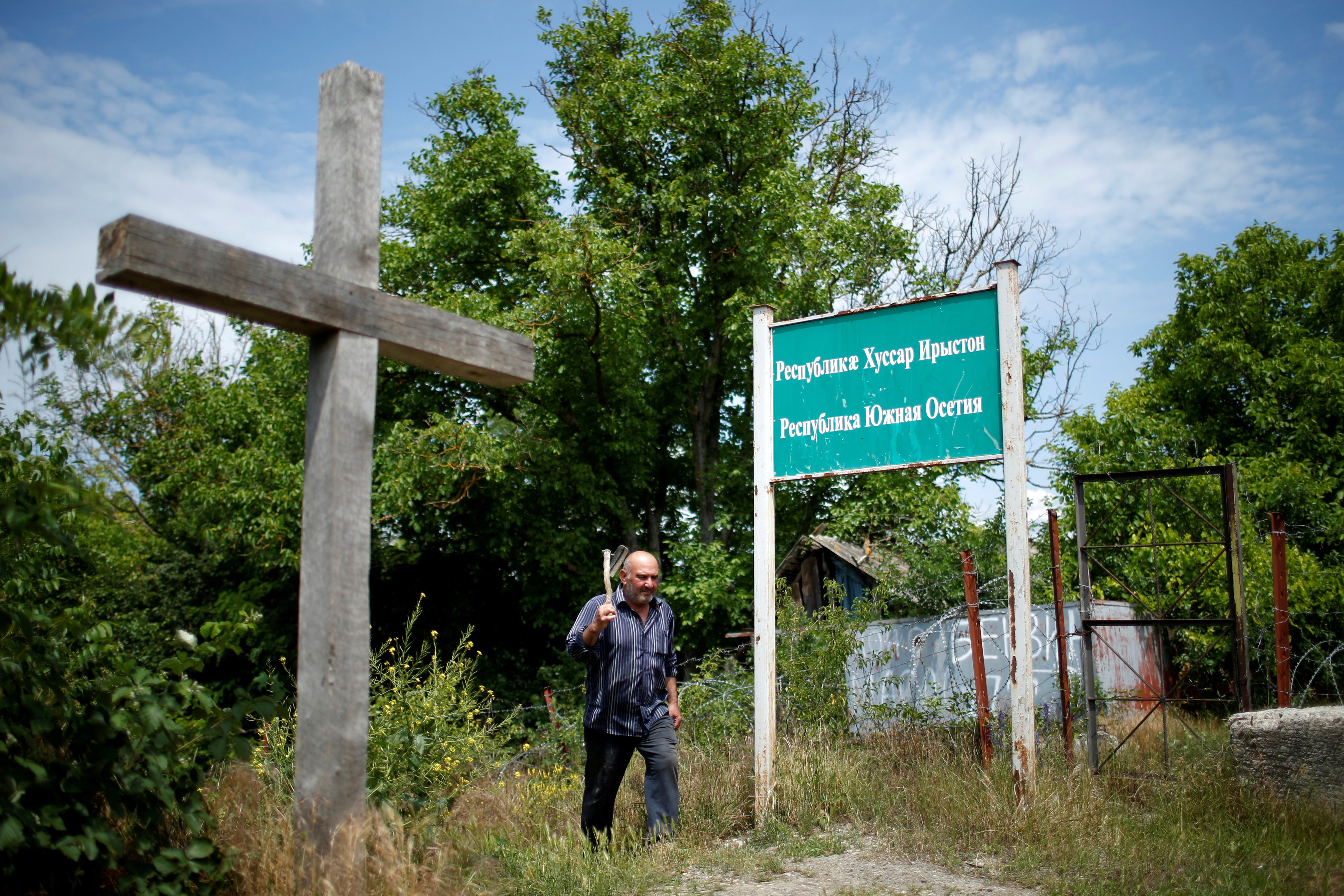 A local resident Mekarishvili walks past a banner "Republic Of South Ossetia" at the borderline on the de facto border of Georgia's breakaway region of South Ossetia in Dvani