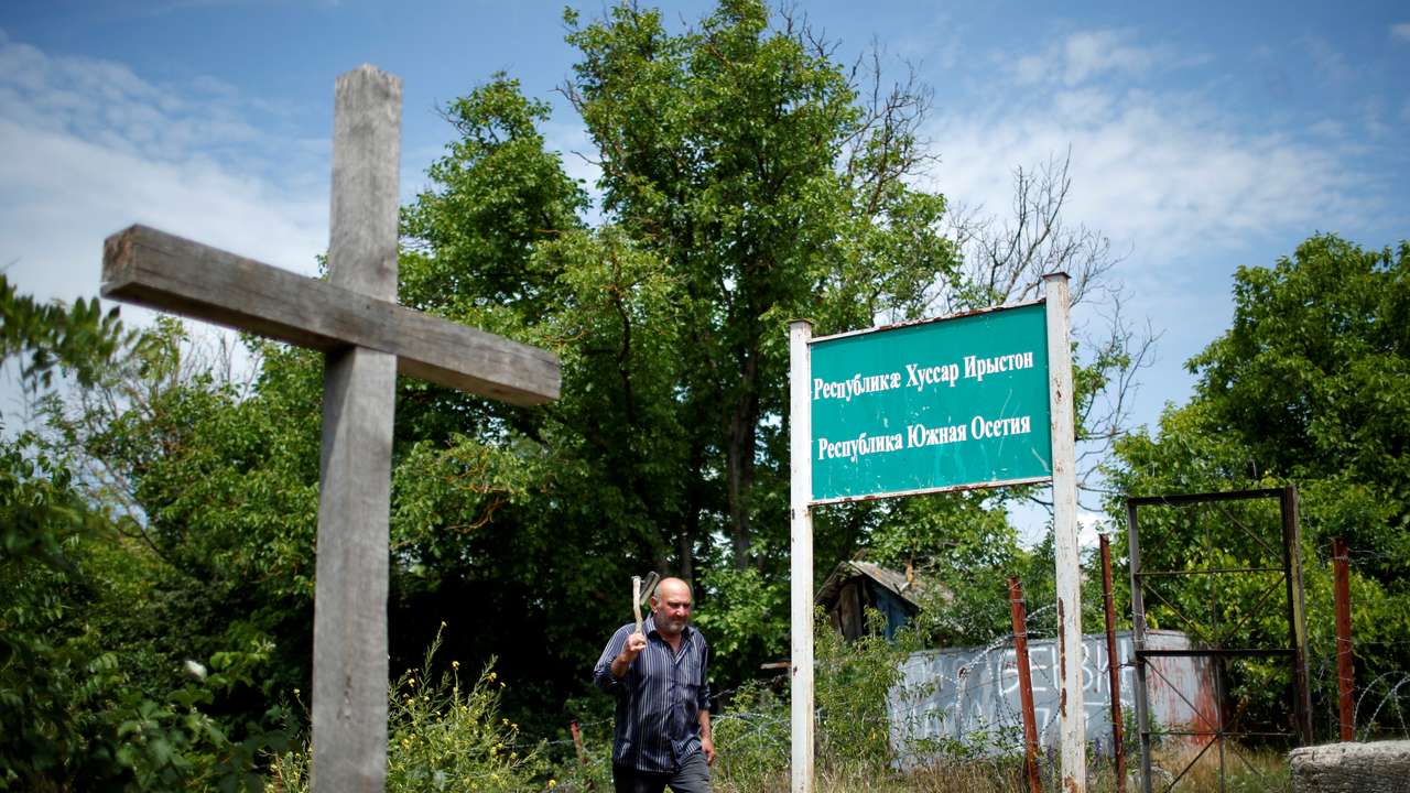 A local resident Mekarishvili walks past a banner "Republic Of South Ossetia" at the borderline on the de facto border of Georgia's breakaway region of South Ossetia in Dvani