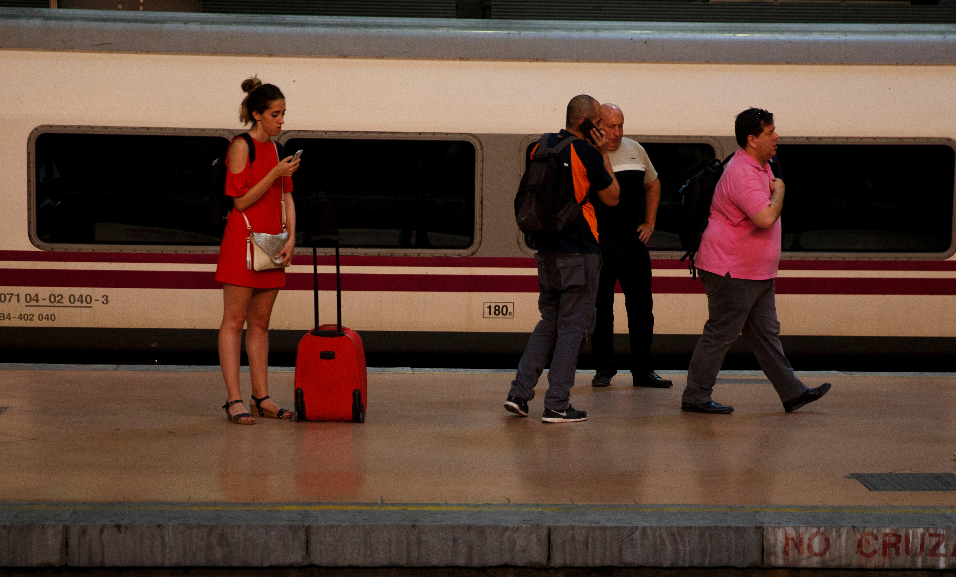 People stand on a platform as they wait for a commuter rail at Atocha train station in Madrid