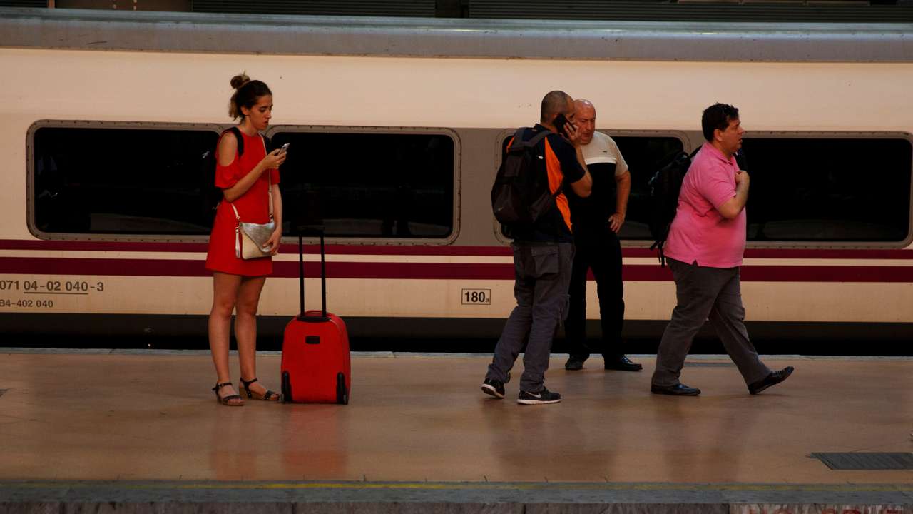 People stand on a platform as they wait for a commuter rail at Atocha train station in Madrid