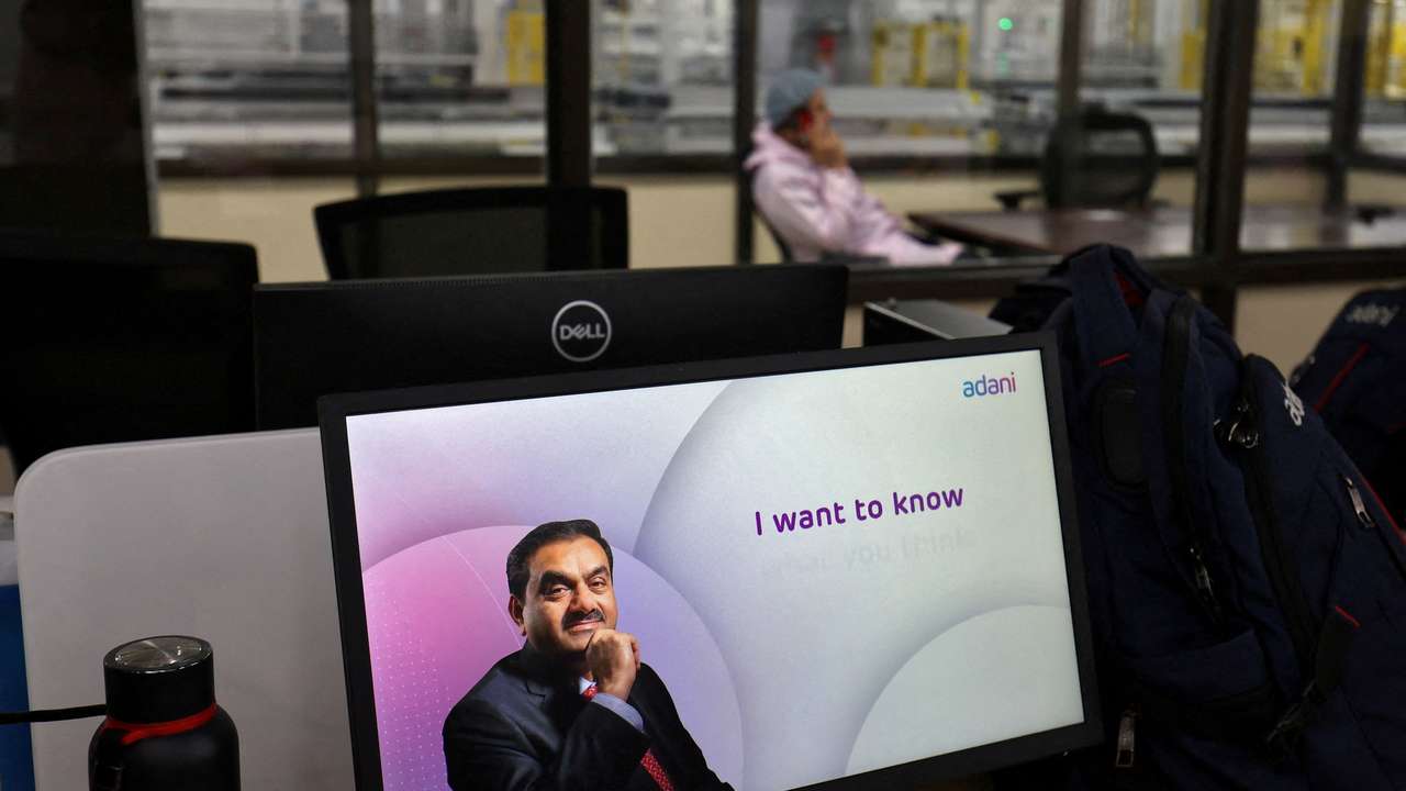 FILE PHOTO: A technician talks on his cell phone at the Photovoltaic Modules assembling plant of Adani Green Energy Ltd (AGEL), in Mundra
