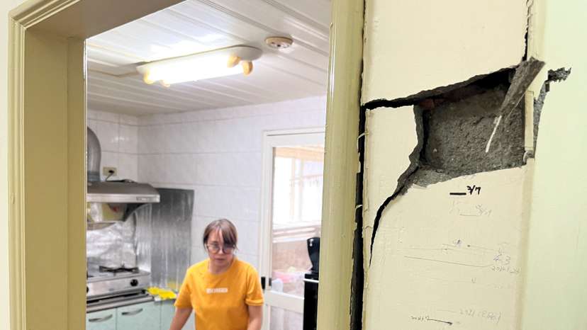 Linda Chen, 48, walks near the damaged walls with marks tracking her son's height over time, while collecting valuables from her apartment following the earthquake, in Hualien