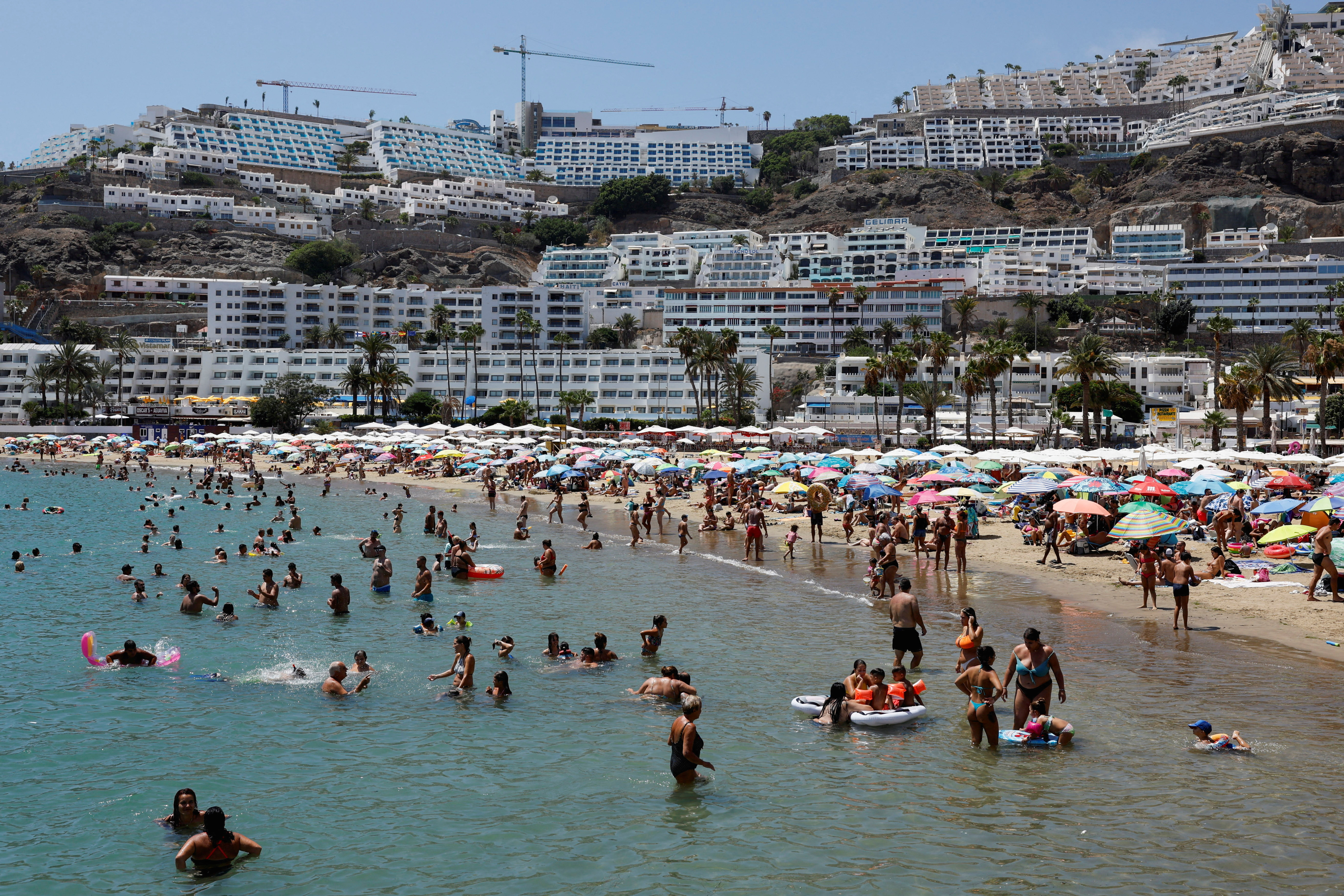 FILE PHOTO: Tourists bathe and sunbathe on the beach of Puerto Rico in the south of the island of Gran Canaria
